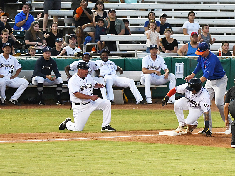 The Missions' Juan Fernandez slides into third with a triple in front of San Antonio manager Phillip Wellman and the Missions' bullpen pitchers in Saturday's victory over the Midland RockHounds at Wolff Stadium. - photo by Joe Alexander